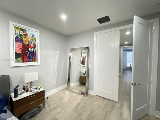 bedroom featuring light wood finished floors, visible vents, and baseboards