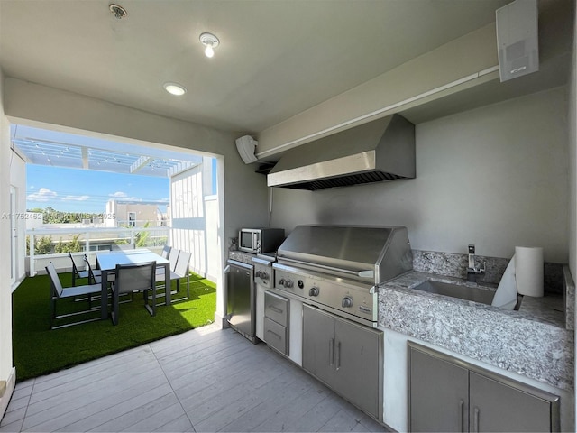 view of patio / terrace featuring outdoor dining space, a sink, a grill, and an outdoor kitchen