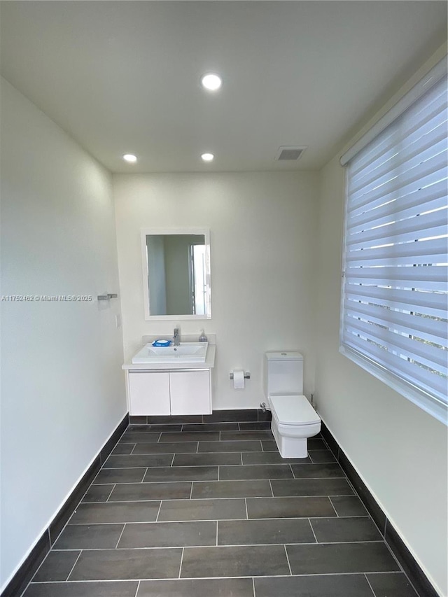 bathroom featuring baseboards, visible vents, toilet, vanity, and recessed lighting