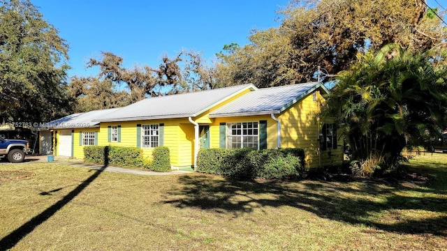 view of front facade with an attached garage, metal roof, and a front yard