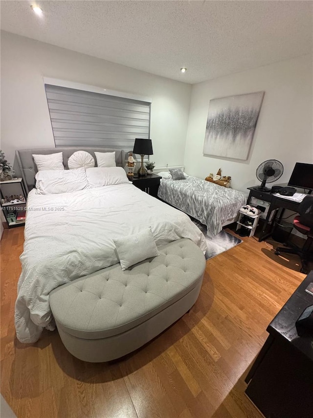 bedroom with a textured ceiling and wood finished floors