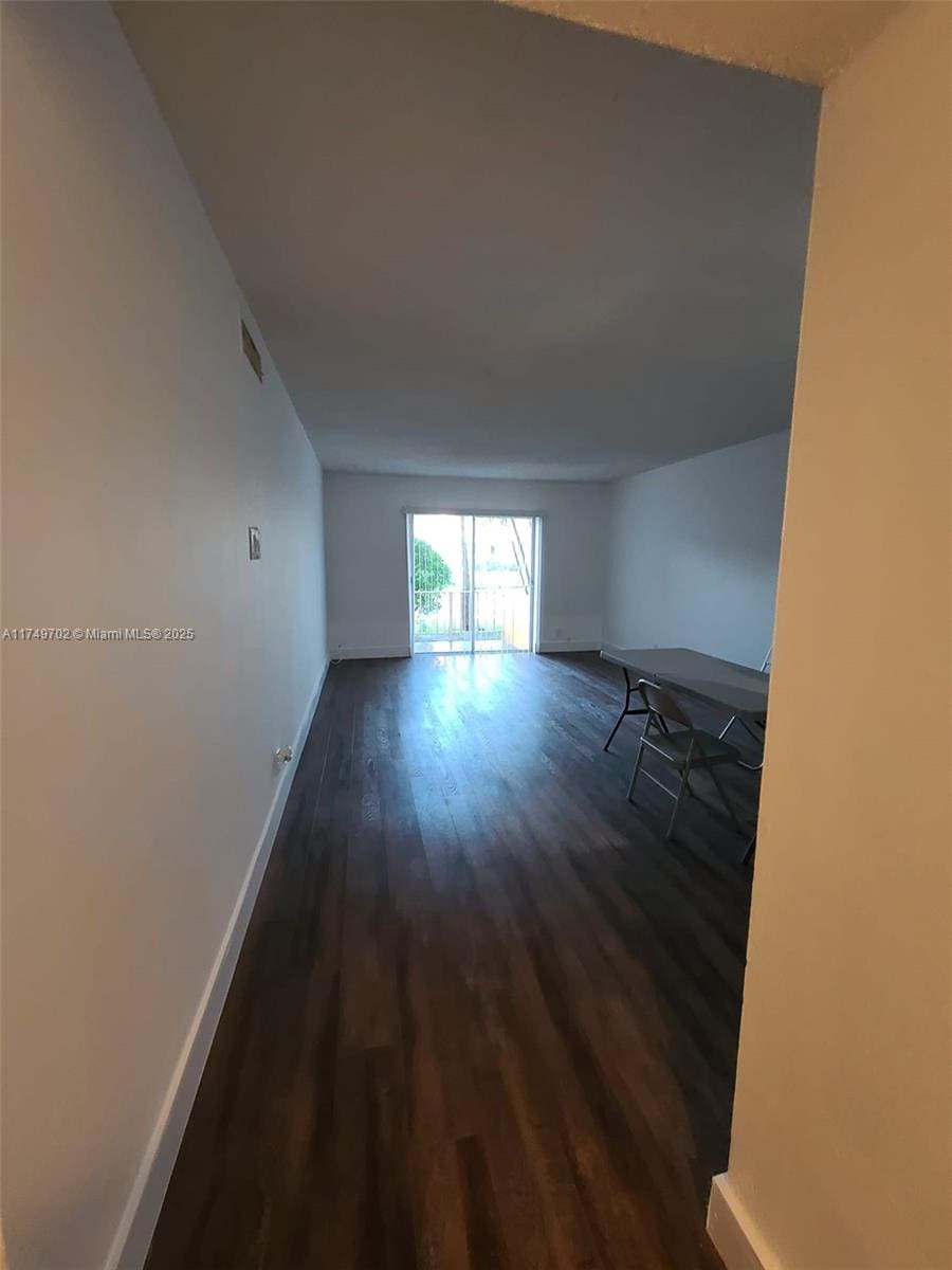 corridor featuring dark wood-type flooring, visible vents, and baseboards