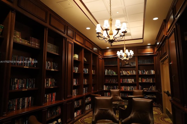 living area featuring a chandelier, a tray ceiling, built in shelves, bookshelves, and recessed lighting