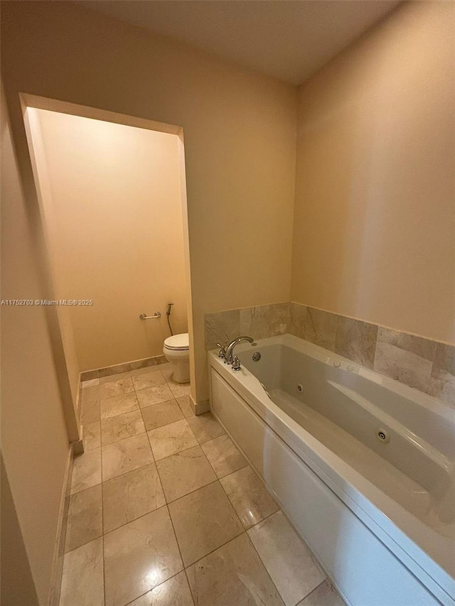 full bath featuring a jetted tub, baseboards, and toilet