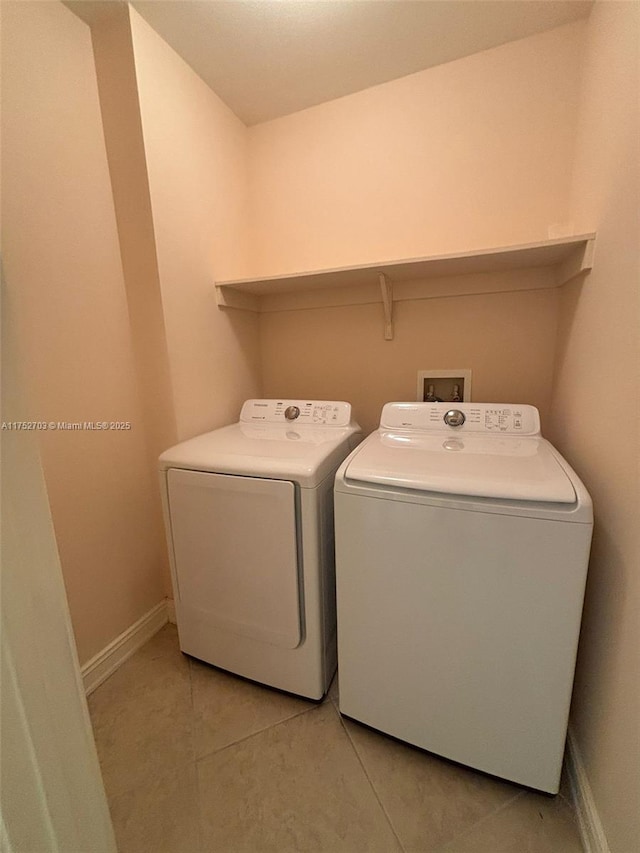 laundry area featuring laundry area, light tile patterned flooring, independent washer and dryer, and baseboards