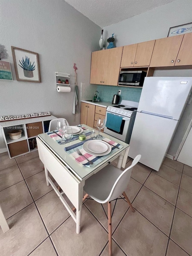 kitchen with a textured ceiling, light countertops, white appliances, and tile patterned flooring