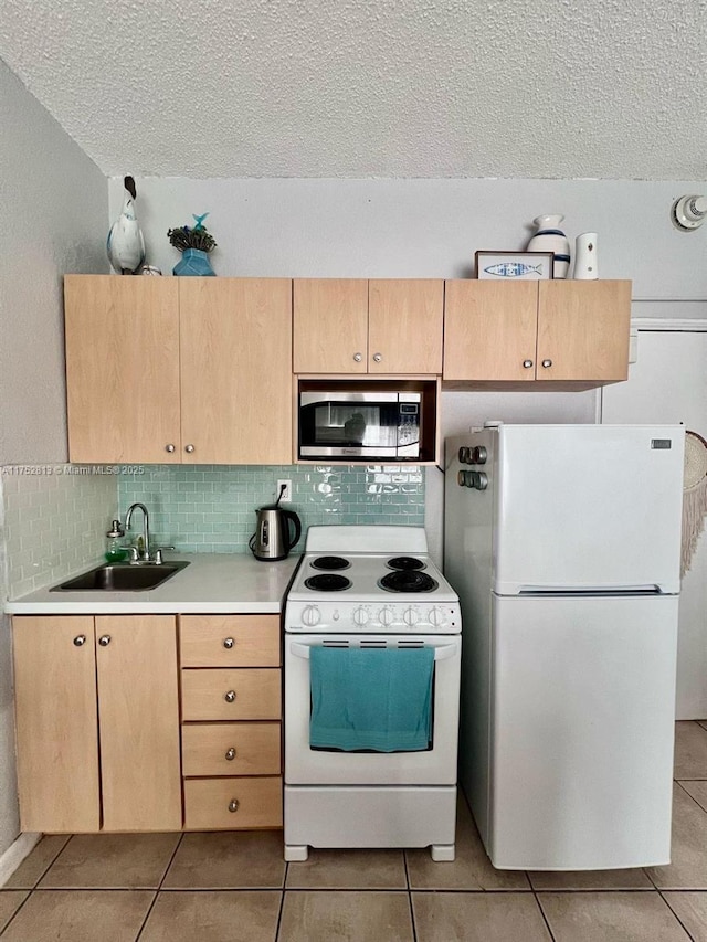 kitchen featuring light tile patterned floors, white appliances, a sink, light countertops, and light brown cabinetry