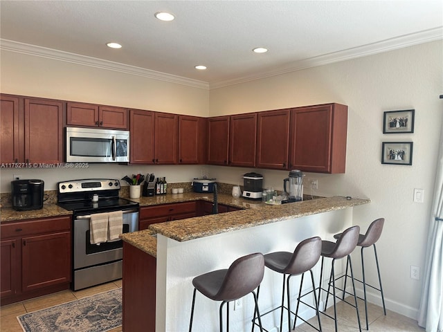 kitchen featuring appliances with stainless steel finishes, crown molding, a peninsula, and a kitchen bar