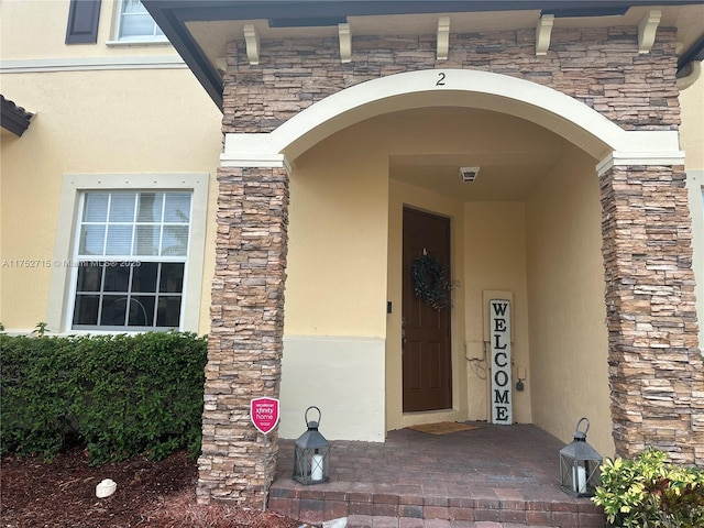 entrance to property featuring stone siding and stucco siding