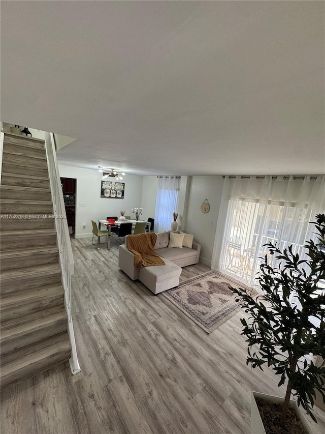 living area featuring stairway, wood finished floors, and baseboards
