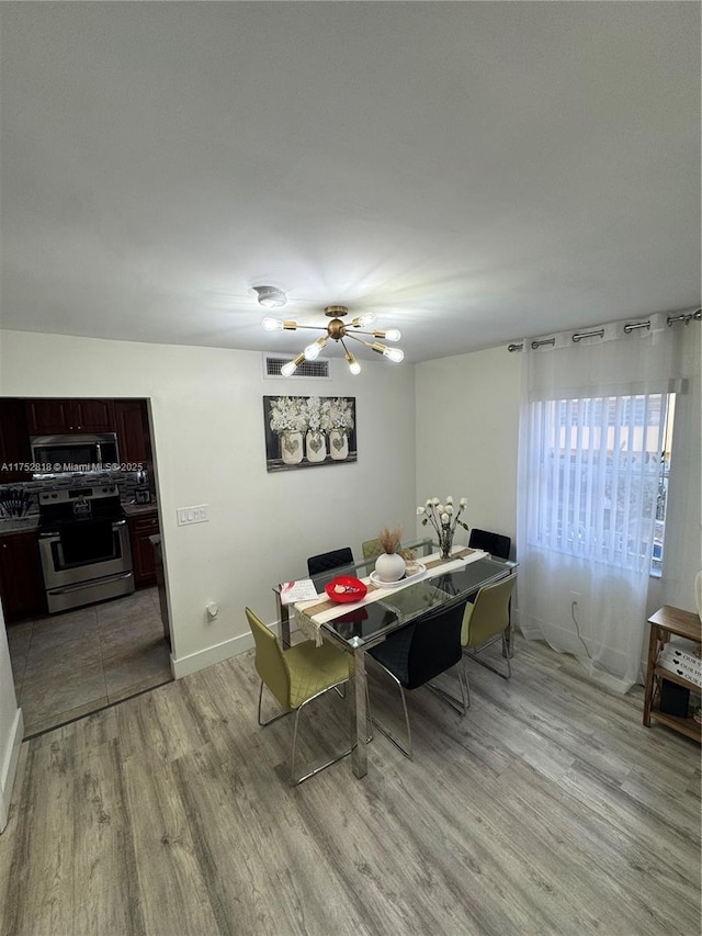 dining area featuring light wood finished floors, a chandelier, and baseboards