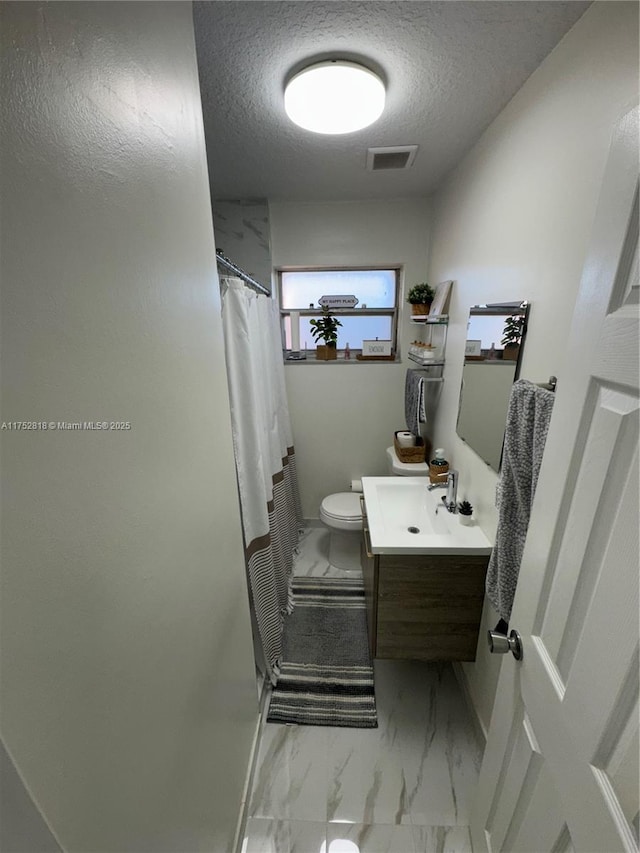 full bathroom featuring marble finish flooring, a textured ceiling, vanity, toilet, and a shower with curtain