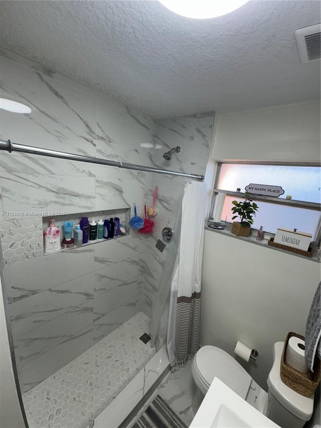 full bath with marble finish flooring, a textured ceiling, a shower stall, and toilet