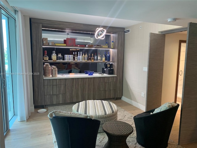 interior space with a dry bar, light wood-style flooring, and baseboards