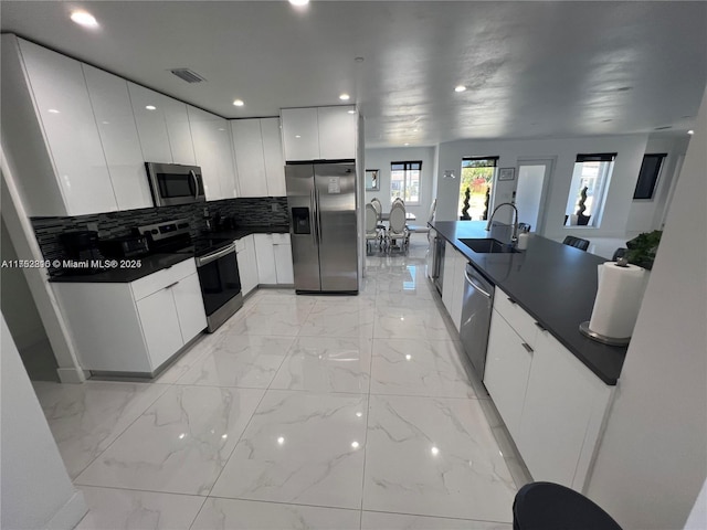 kitchen featuring dark countertops, modern cabinets, stainless steel appliances, and a sink