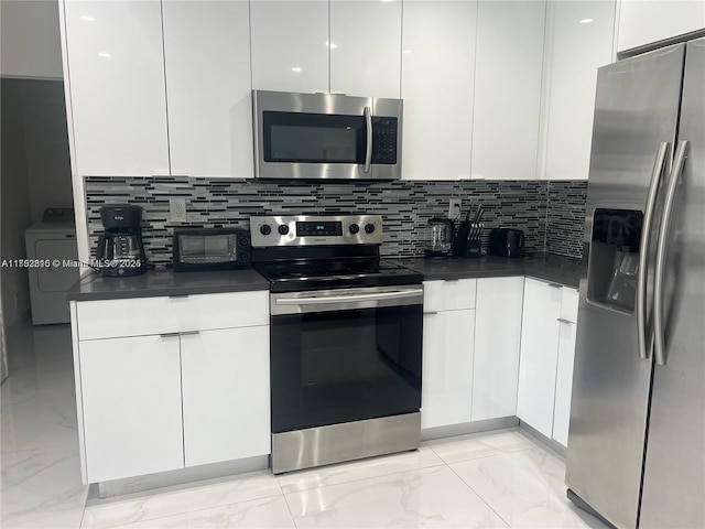 kitchen featuring appliances with stainless steel finishes, washer / dryer, and white cabinetry