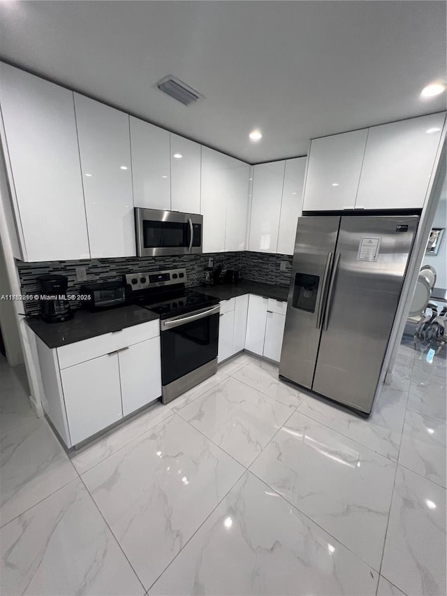 kitchen featuring visible vents, dark countertops, modern cabinets, appliances with stainless steel finishes, and white cabinetry