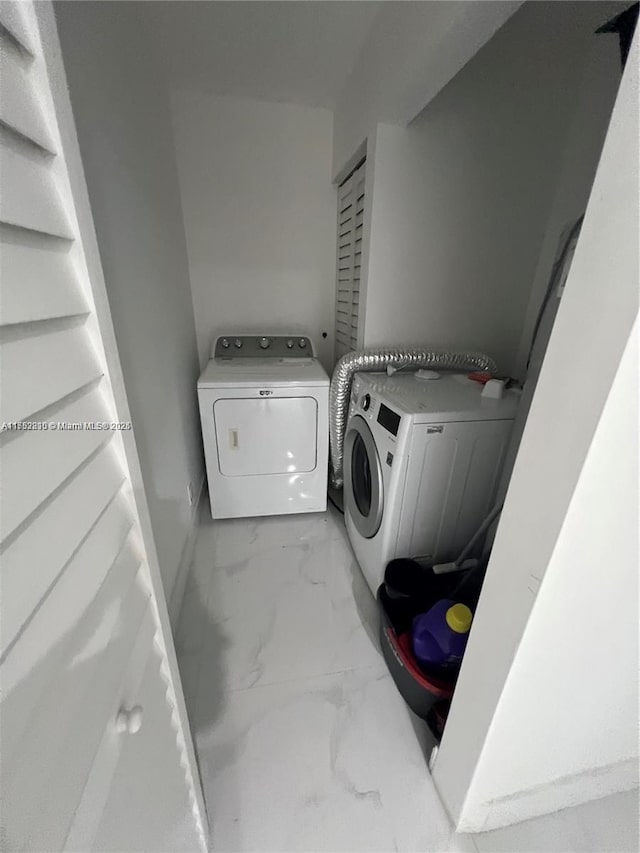 washroom featuring laundry area, baseboards, marble finish floor, and washing machine and clothes dryer