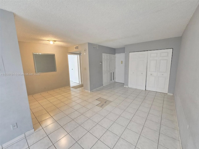 unfurnished room with visible vents, a textured ceiling, and light tile patterned flooring