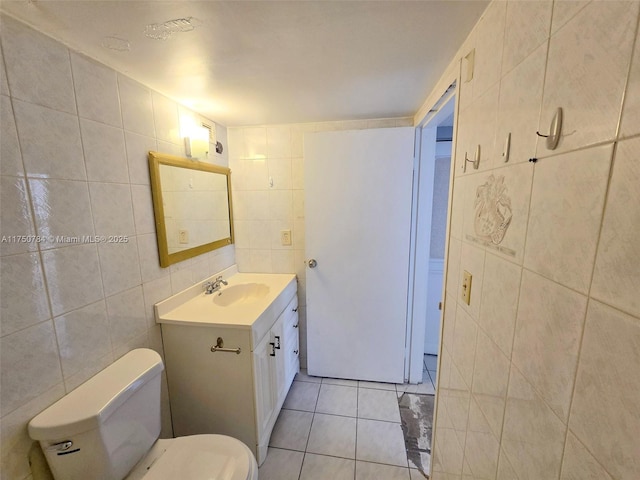 half bath with toilet, vanity, tile walls, and tile patterned floors