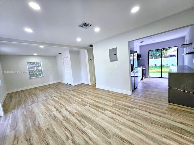 spare room with light wood-type flooring, electric panel, visible vents, and baseboards