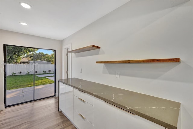 kitchen with light wood finished floors, dark stone counters, modern cabinets, white cabinetry, and open shelves