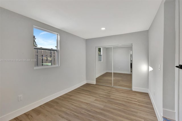 unfurnished bedroom featuring baseboards, a closet, recessed lighting, and light wood-style floors