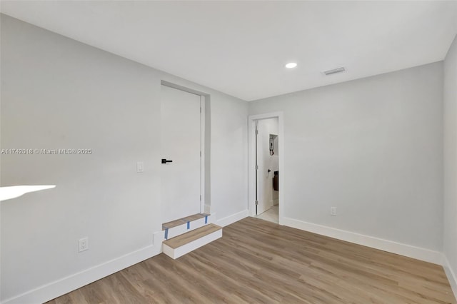 spare room with light wood-type flooring, visible vents, baseboards, and recessed lighting