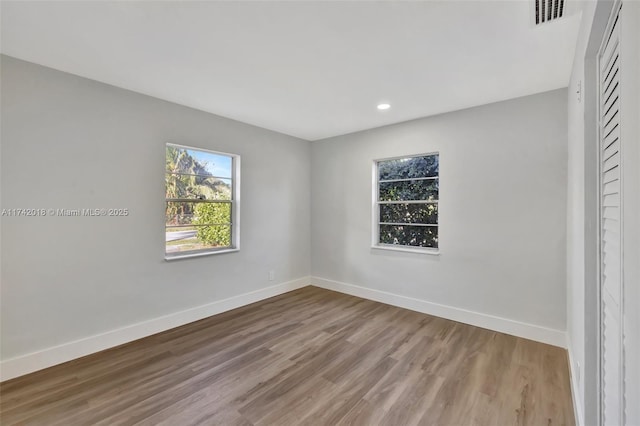 empty room featuring wood finished floors, visible vents, and baseboards