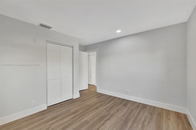 unfurnished bedroom with light wood finished floors, recessed lighting, a closet, visible vents, and baseboards