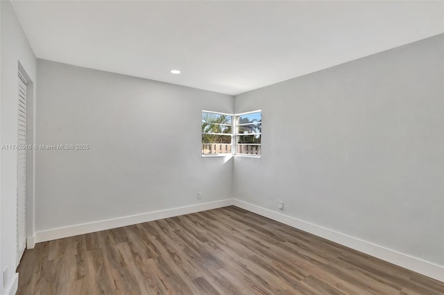 empty room featuring recessed lighting, wood finished floors, and baseboards