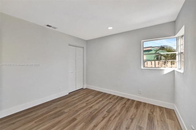 spare room featuring recessed lighting, wood finished floors, visible vents, and baseboards