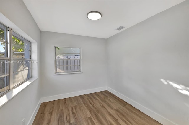 empty room with baseboards, visible vents, and wood finished floors