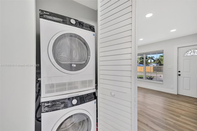 laundry area with laundry area, baseboards, light wood-style floors, stacked washing maching and dryer, and recessed lighting