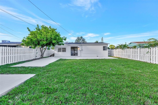 rear view of property featuring a patio area, a yard, a fenced backyard, and stucco siding