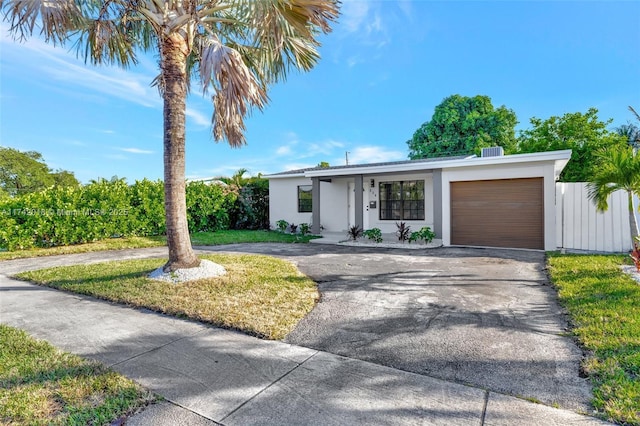 view of front of home with a garage, stucco siding, driveway, and fence