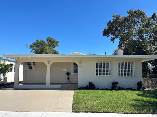 single story home featuring driveway, a front lawn, and stucco siding