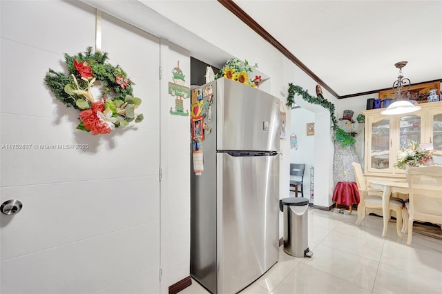 kitchen featuring hanging light fixtures, light tile patterned flooring, ornamental molding, and freestanding refrigerator