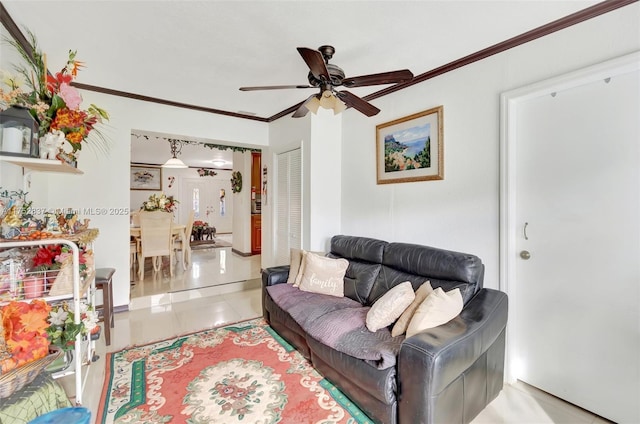 living room with ceiling fan, ornamental molding, and tile patterned floors