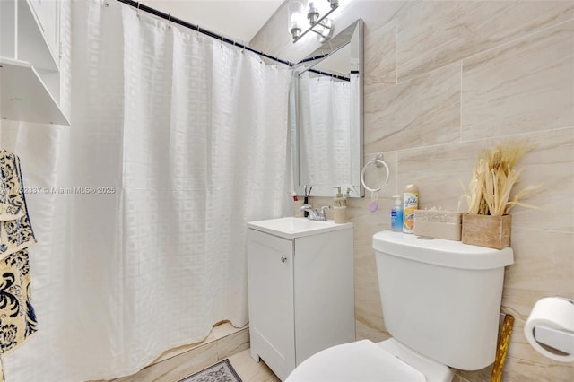 bathroom featuring toilet, a shower with shower curtain, vanity, and tile walls