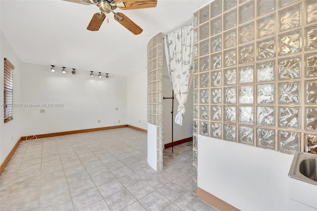 interior space featuring track lighting, ceiling fan, baseboards, and light tile patterned floors