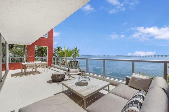 balcony featuring a water view and an outdoor living space