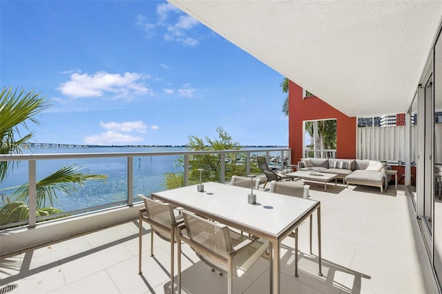 balcony with outdoor dining space, a water view, and an outdoor hangout area