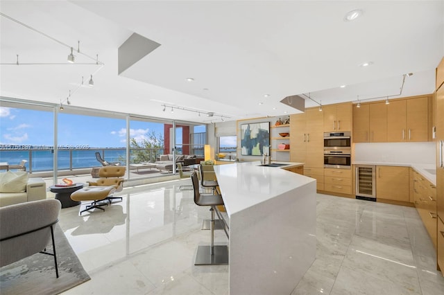 kitchen featuring wine cooler, open floor plan, a sink, and light brown cabinetry