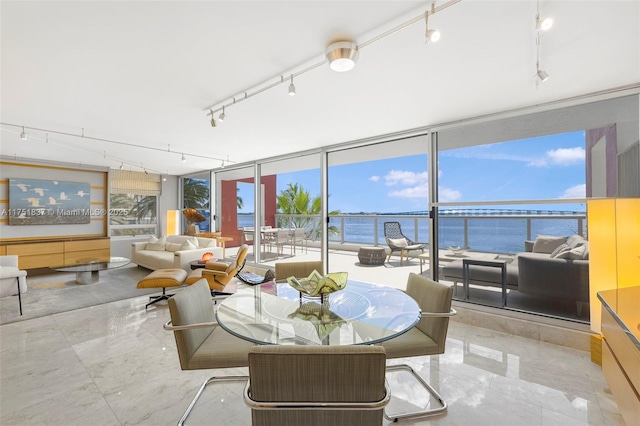 sunroom featuring a water view and track lighting