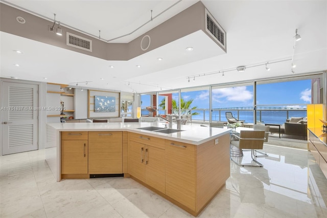 kitchen with visible vents, light countertops, a sink, and open floor plan