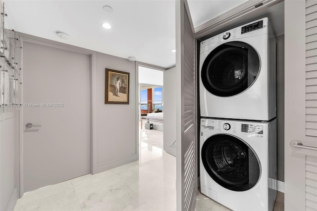 laundry area with laundry area, stacked washer / dryer, and recessed lighting