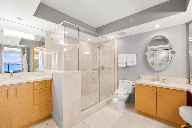 bathroom featuring toilet, a stall shower, two vanities, and a sink