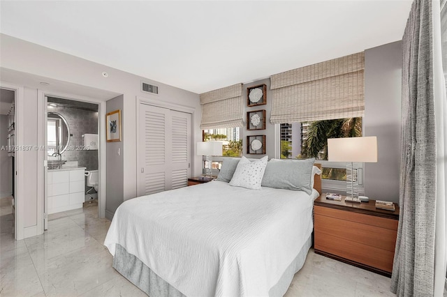 bedroom with a closet, visible vents, marble finish floor, and ensuite bathroom