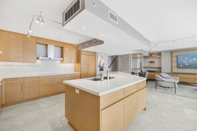 kitchen featuring cooktop, visible vents, a sink, wall chimney range hood, and modern cabinets